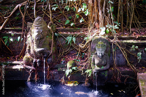 Asian art and religion. Balinese stone sculptures of Ganesha God near pond in jungle. photo
