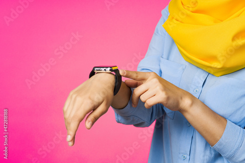 cheerful woman in yellow hijab electronic watch technology user pink background