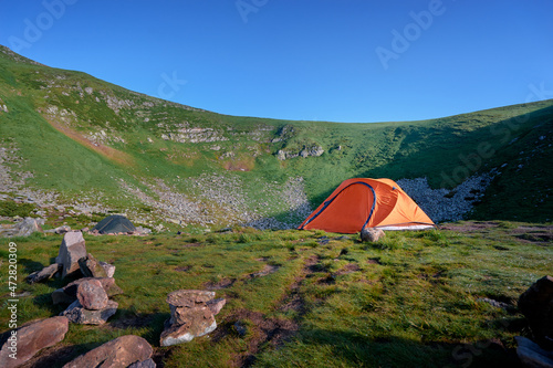 Tourism and traveling concept. Beautiful summer landscape with mountains and tourist tent.