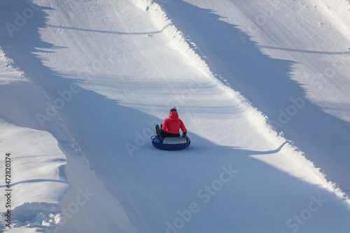 The girl is rolling down the mountain on a tubing