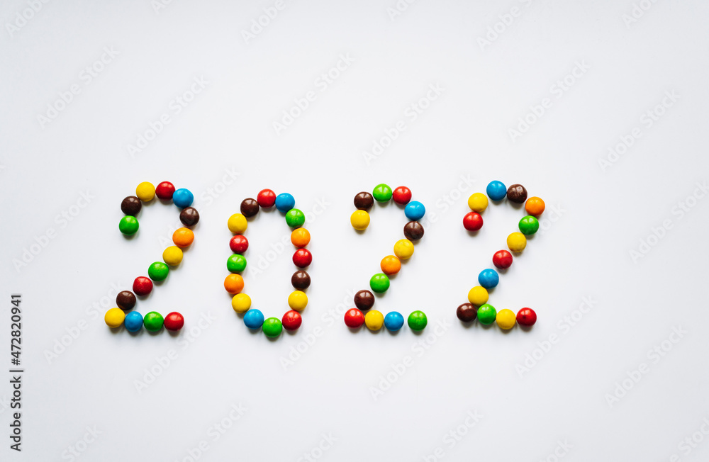 Year 2022 laid out from round multicolored candies on white background Year 2022 laid out from round multicolored candies on white background