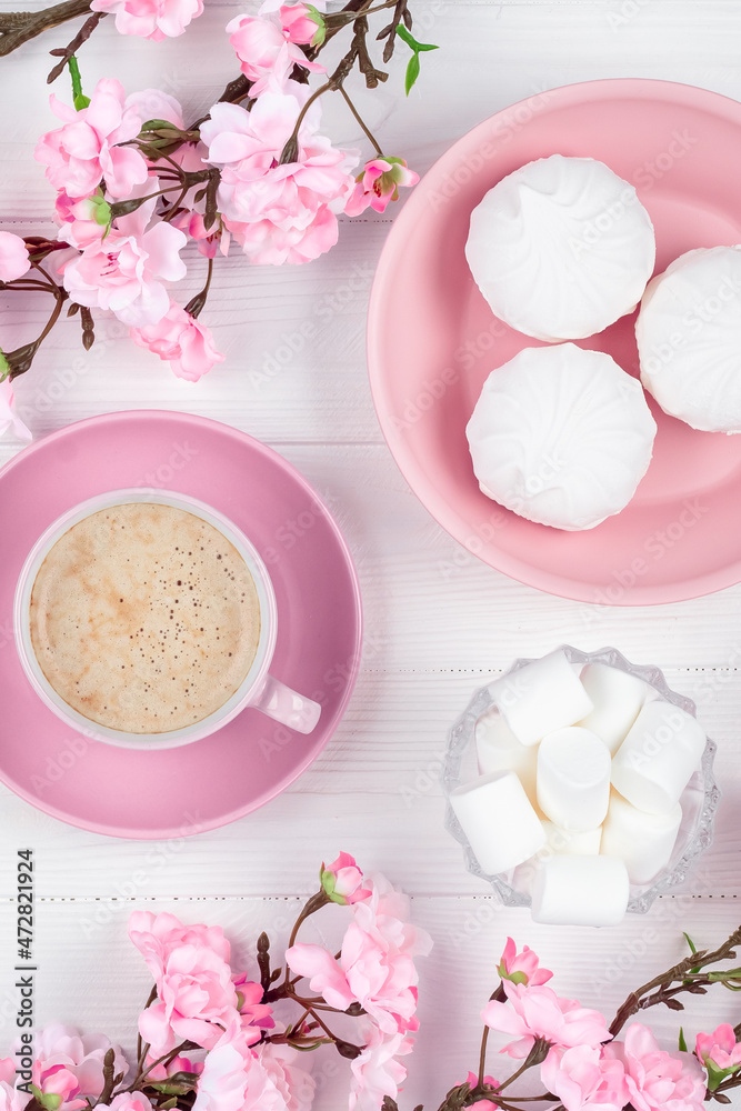 Coffee cup and marshmallow in the morning for breakfast. Spring flowers and dessert on white wooden background. Flat lay. Pastel pink colored card for International Women's Day. Food still life. Coffee cup and marshmallow in the morning for breakfast. Spring flowers and dessert on white wooden background. Flat lay. Pastel pink colored card for International Women's Day. Food still life.
