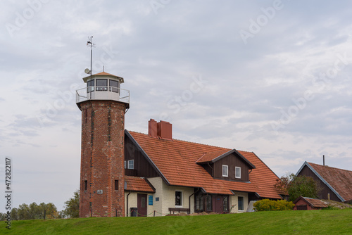 Uostadvaris lighthouse is in the shape of a regular octagon, the edges of the walls are decorated with green glazed bricks, the walls are made of red brick masonry. photo