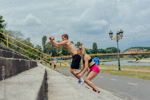 Side view picture of active sporty couple jumping up on stairs in a park