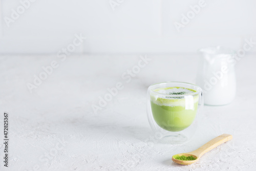 Matcha latte tea in a glass on a light background. Horizontal orientation, copy space.