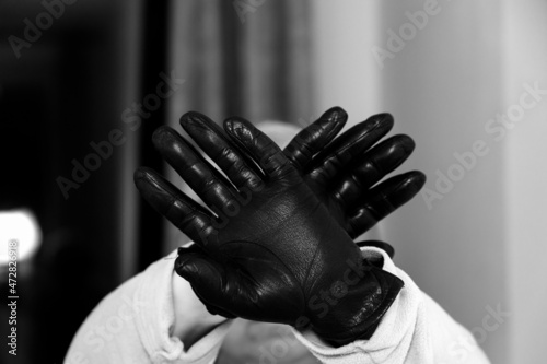 Black mittens. Woman covers her face with her hands