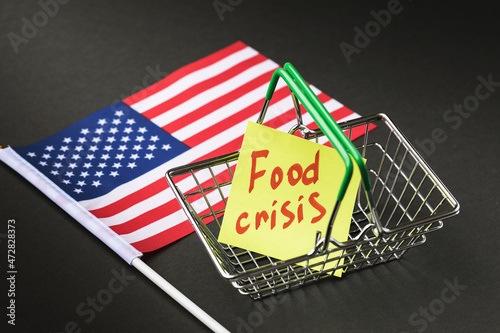 American flag and note with text in empty food basket on dark background, USA food crisis concept photo