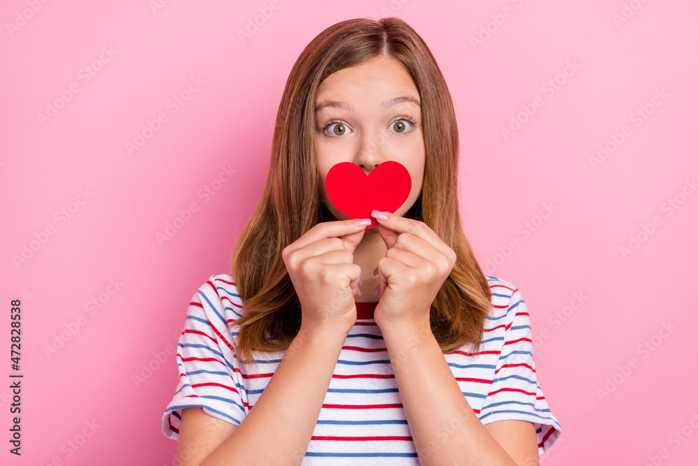 Photo of cute little brown hairdo girl hold heart wear striped t-shirt isolated on pink color background Photo of cute little brown hairdo girl hold heart wear striped t-shirt isolated on pink color background
