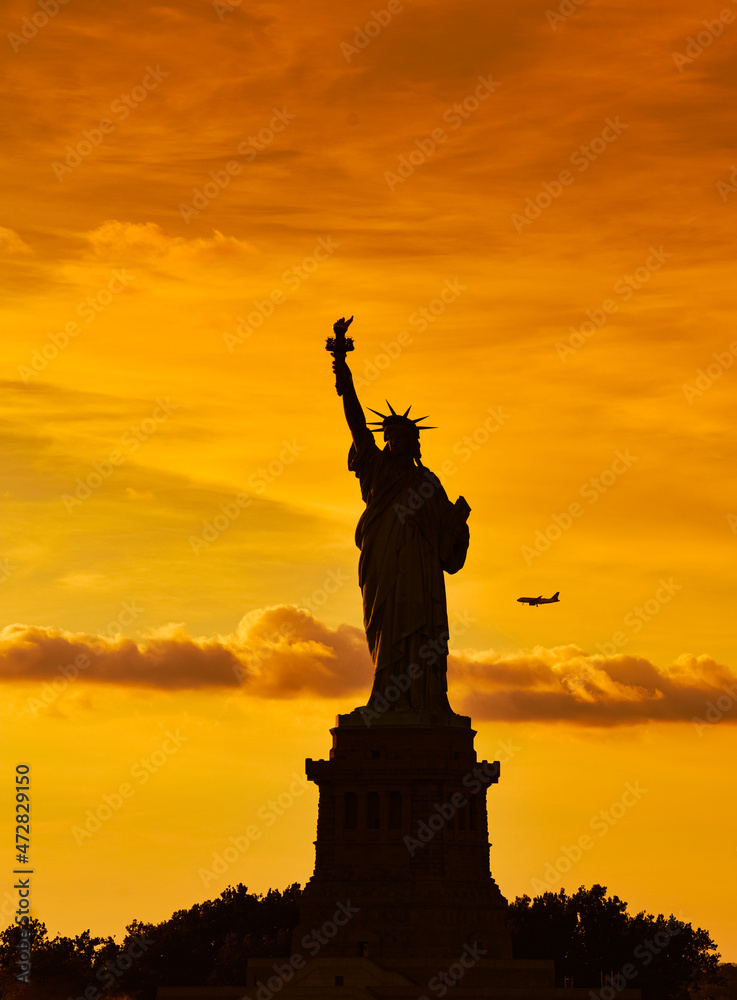 Travel to Manhattan, visit New York. Amazing summer sunset over Statue of Liberty with spectacular dramatic sky. One of the most known landmark in United States. Travel to Manhattan, visit New York. Amazing summer sunset over Statue of Liberty with spectacular dramatic sky. One of the most known landmark in United States.