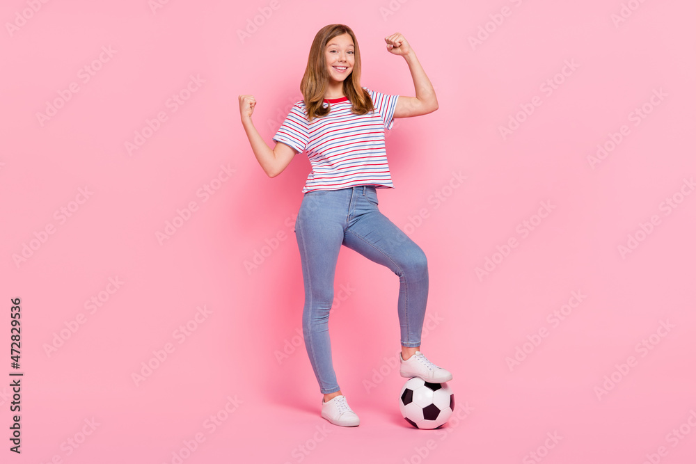 Full size photo of cute little blond girl play football wear t-shirt jeans shoes isolated on pink background