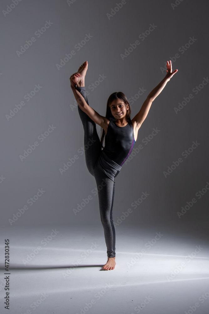 child doing artistic gymnastics movements, wearing gym clothes, photography taken in a studio