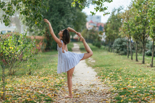 beautiful girl in white dress doing yoga poses in the autumn park, balance, fitness, stretching and relaxation