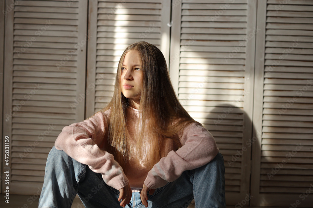 A teenage girl is sitting on the floor. Problems of teenagers. A girl with long hair. Pimples and scars. A natural portrait. No makeup and retouching. Space for text. High-quality photography A teenage girl is sitting on the floor. Problems of teenagers. A girl with long hair. Pimples and scars. A natural portrait. No makeup and retouching. Space for text. High-quality photography