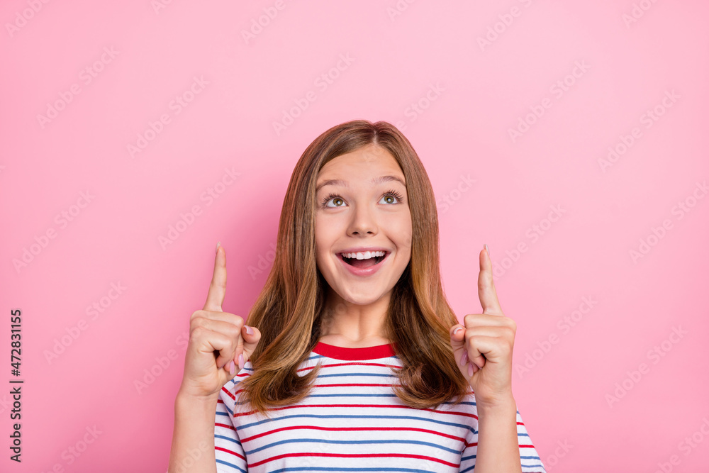 Photo of impressed teenager girl look up wear striped t-shirt isolated on pink color background Photo of impressed teenager girl look up wear striped t-shirt isolated on pink color background