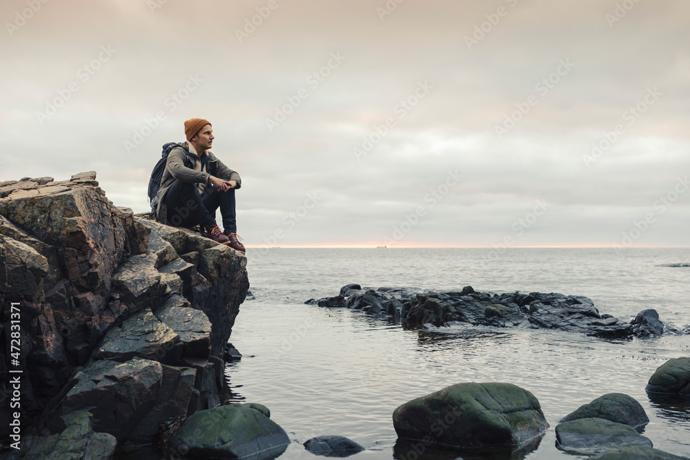 Man contemplating while sitting on rock by sea Man contemplating while sitting on rock by sea