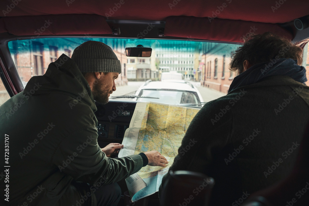 Male friends examining map while sitting in camping van during road trip Male friends examining map while sitting in camping van during road trip