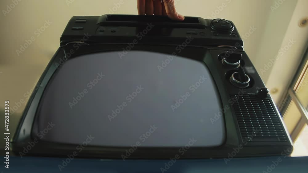 Man Hand Inserting VHS Cassette in Old Video Recorder, A Retro Television Turns On Green Screen. Low Angle View. 4K Resolution.