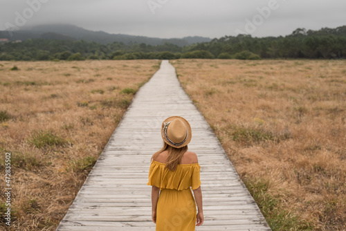 Anonymous woman walking on boardwalk in countryside photo