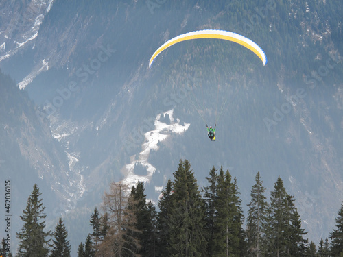2men flying a paraglider over a valley in winter