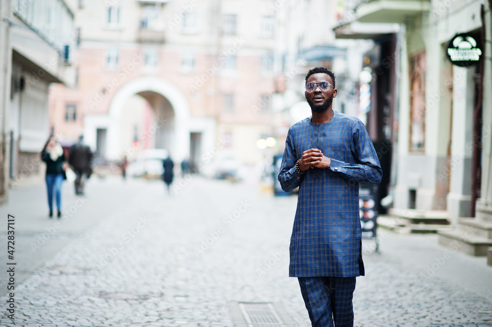 African guy in blue authentic costume, eyeglasses. Fashionable nigerian man.
