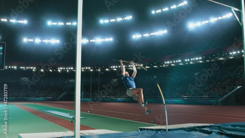 Pole Vault Jumping Championship: Professional Male Athlete Running with Pole Successfully Jumping over Bar and Landing on His Feet, Celebrates Record Setting Victory with Stadium Crowd Cheering