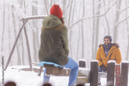 Couple sitting on seesaw having fun outdoor on snowy winter day