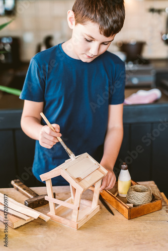Boy painting wooden bird feeder
