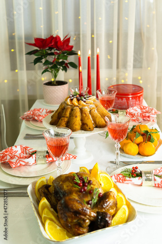 Beautifully decorated festive table with baked chicken, homemade cake, glasses of wine and candles. Baked chicken for Thanksgiving, Christmas and New Year. 