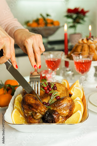 Festive baked chicken. Women's hands with red manicure cut baked chicken for Thanksgiving, Christmas and New Year.