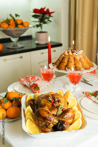 Beautifully decorated festive table with baked chicken, homemade cake, glasses of wine and candles. Baked chicken for Thanksgiving, Christmas and New Year.