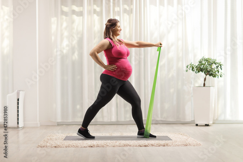 Pregnant woman exercising with a resistance band at home