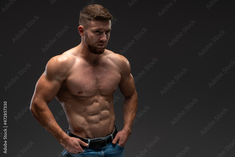 Waist up portrait view of the bodybuilder in good shape against dark background. Man posing and showing his muscle definition Waist up portrait view of the bodybuilder in good shape against dark background. Man posing and showing his muscle definition