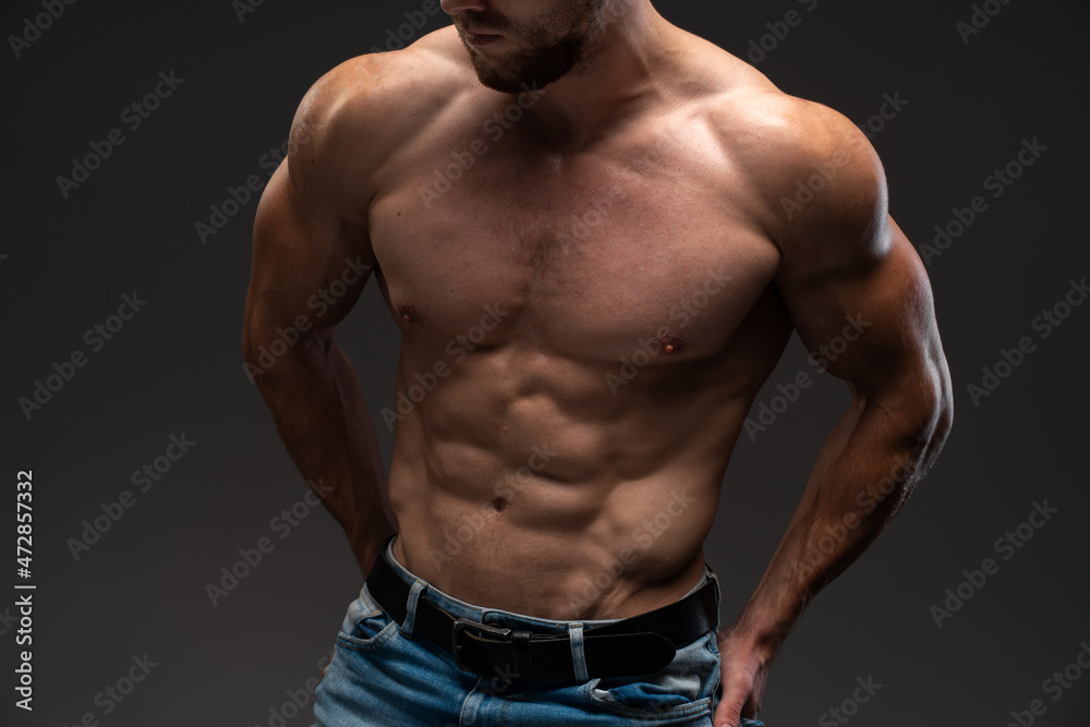 Cropped view of the beautiful and muscular caucasian man posing over the dark background. Sportive body concept