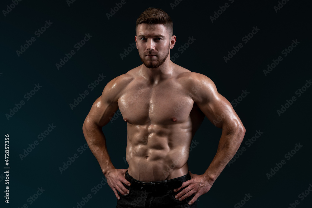 Bodybuilder posing on black background. Healthy muscular caucasian man on dark background. Beautiful sporty guy male power concept