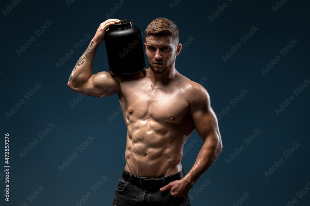 Waist up portrait view of the sporty man holding bottle with protein beverage and looking to the camera. Proper nutrition concept. Stock photo