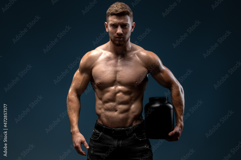 Caucasian sporty man holding shaker with protein beverage and looking to the camera. Proper nutrition concept. Stock photo