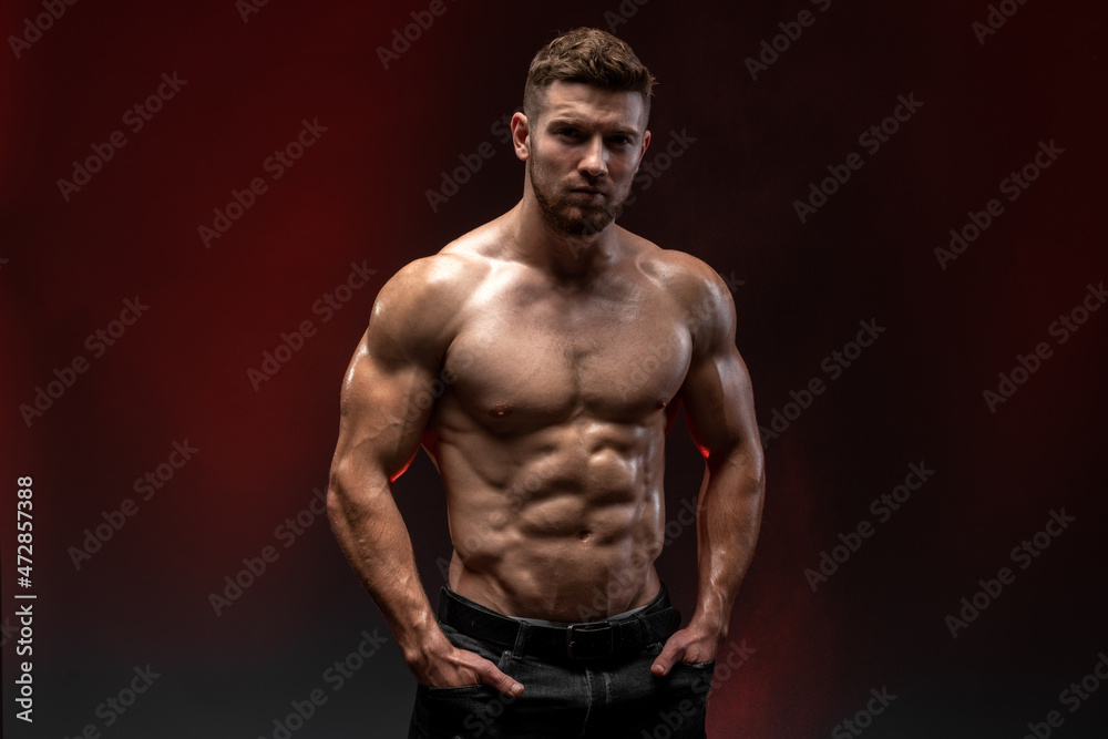 Fitness model showing his perfect body isolated on dark background. Bodybuilder man with perfect abs, shoulders, biceps, triceps and chest. Strong athletic man concept Fitness model showing his perfect body isolated on dark background. Bodybuilder man with perfect abs, shoulders, biceps, triceps and chest. Strong athletic man concept