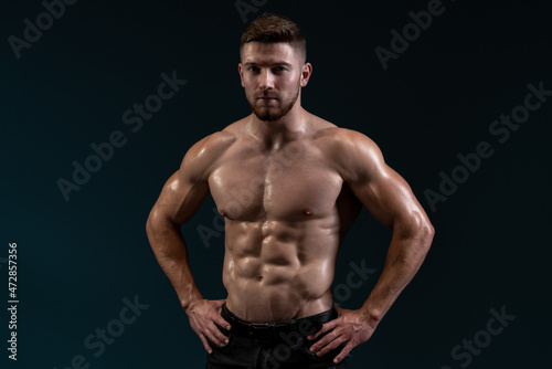 Bodybuilder posing on black background. Healthy muscular caucasian man on dark background. Beautiful sporty guy male power concept