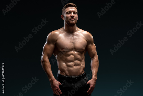 Healthy muscular caucasian man on dark background. Bodybuilder posing on black background. Beautiful sporty guy male power concept