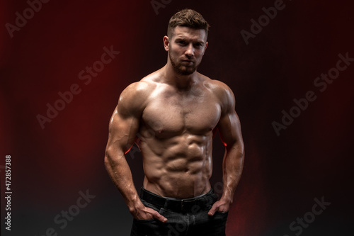 Fitness model showing his perfect body isolated on dark background. Bodybuilder man with perfect abs, shoulders, biceps, triceps and chest. Strong athletic man concept © speed300