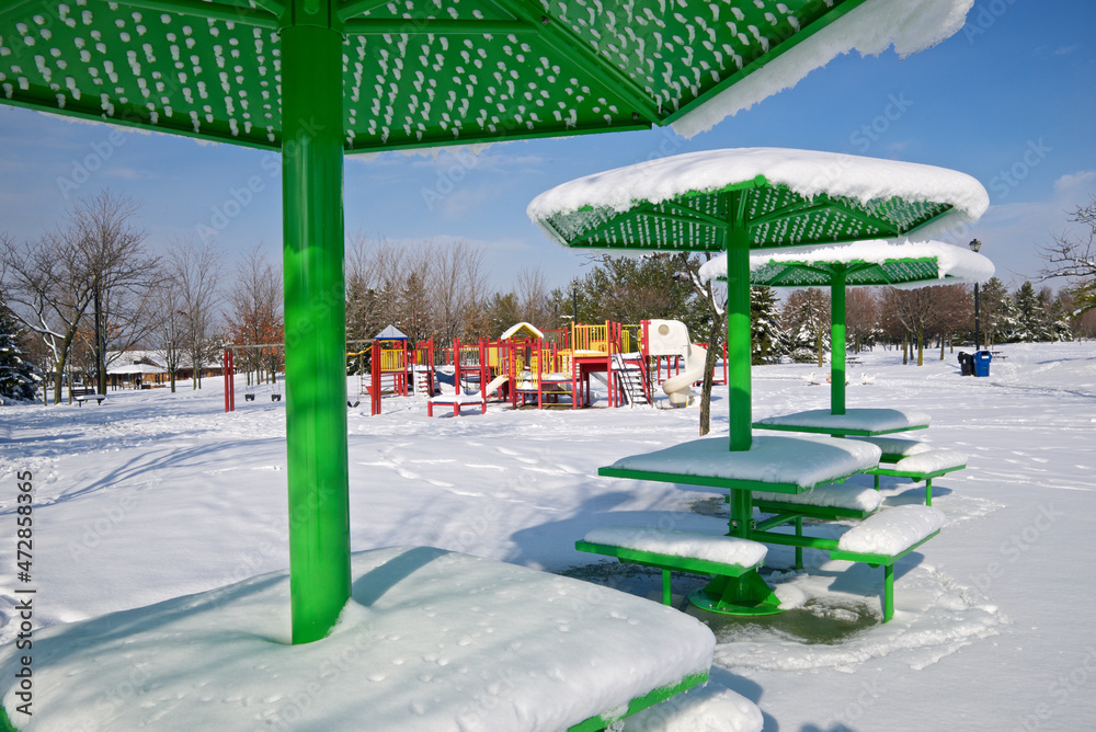 Park bench covered with snow in the public park on winter
