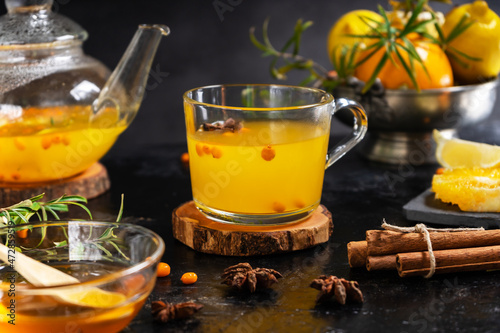Mug and tea pot with sea buckthorn beverage made with honey, orange, lemon, cinnamon. anise stars 