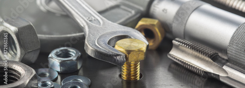 Fotografie Wrench tightens brass bolt in steel billet