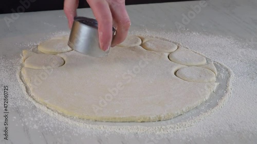 Woman cuts out dough circles for making sweet buns, dounuts. photo