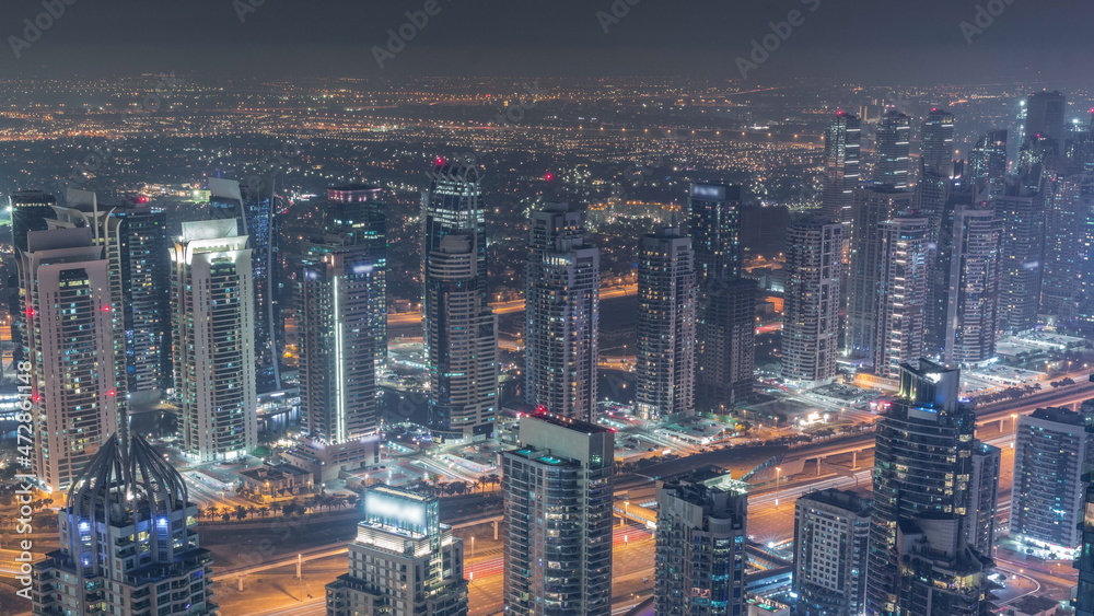 JLT skyscrapers and Dubai marina near Sheikh Zayed Road aerial all night timelapse. Residential buildings