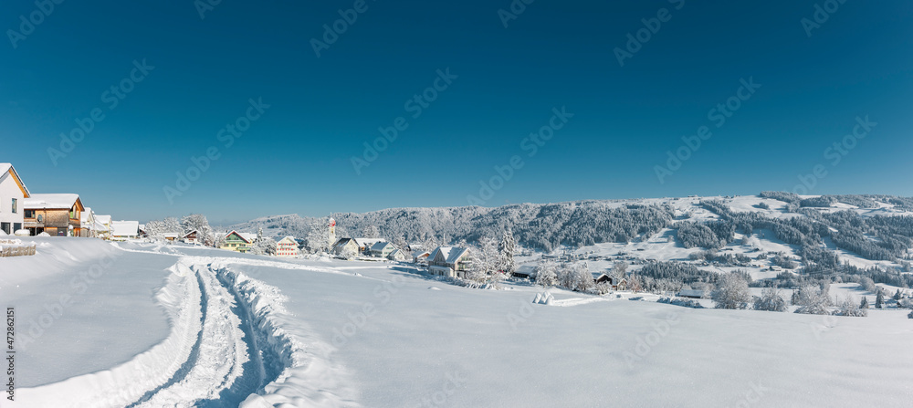 Verschneiter Ort Scheffau im Allgäu an einem sonnigen Wintertag