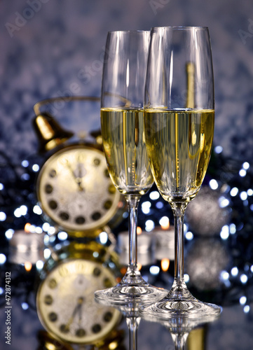 Two glasses of champagne at New Year's Eve party golden shiny background stock images. Glasses champagne against holiday lights stock photo. New Year party still life with champagne and clock images