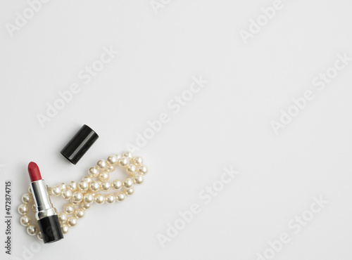 Red lipstick and white pearl necklace isolated on white background. Flat lay. photo