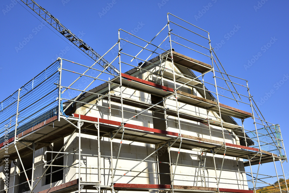 Gerüst an einem neu gebauten Wohnhaus im Rohbau in einem Neubaugebiet Gerüst an einem neu gebauten Wohnhaus im Rohbau in einem Neubaugebiet