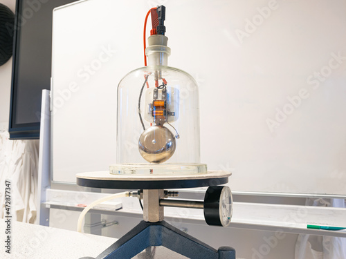 Electric bell is placed under a bell jar where the air is vacuumed through a hose. Sound becomes less and less audible. Scientific experiment, used in physics class. photo
